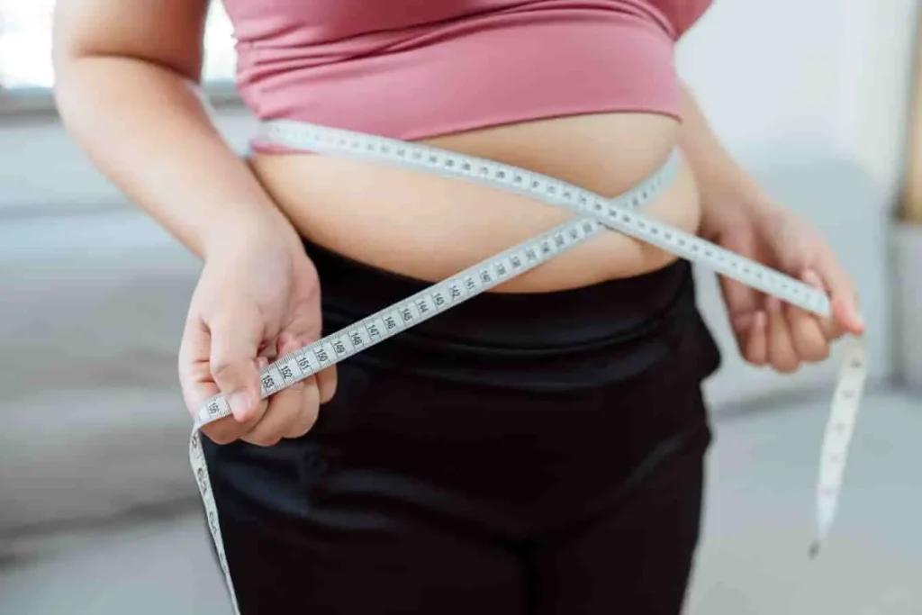 Personne mesurant son tour de taille, illustrant une prise de poids potentielle liée à l’utilisation de Colpotrophine ovule.