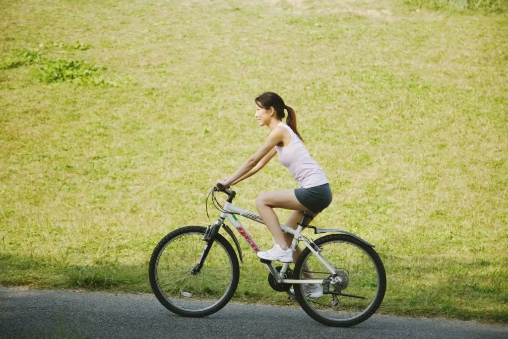 Cycliste en plein effort sur piste entourée de verdure représentant un sport d’endurance pour perdre du ventre