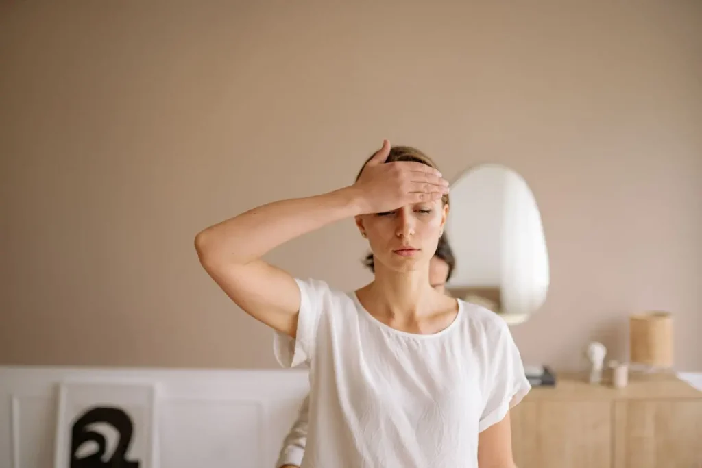 Personne en chemise blanche yeux fermés main sur le front, image illustrant fatigue ou inconfort pouvant évoquer effets secondaires liés à la consommation de chlorella.
