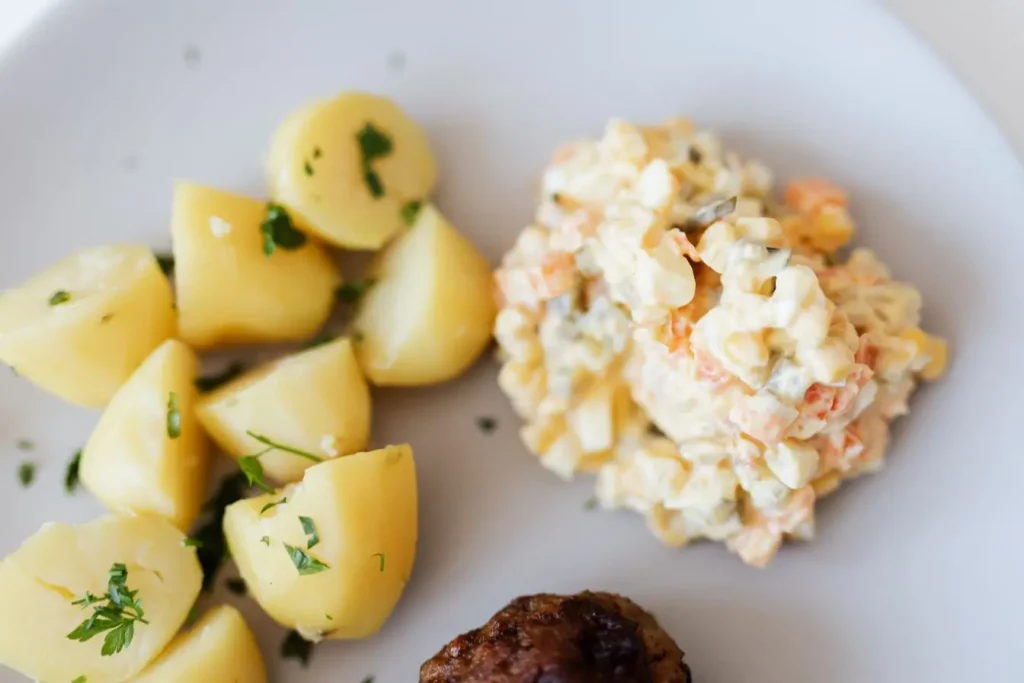 Assiette avec pommes de terre persillées, salade crémeuse et boulette, image illustrant un repas équilibré adapté à une alimentation anti-candida.