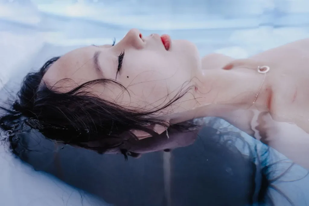 Visage détendu partiellement immergé dans eau claire, image illustrant une séance de cryothérapie corps entier.