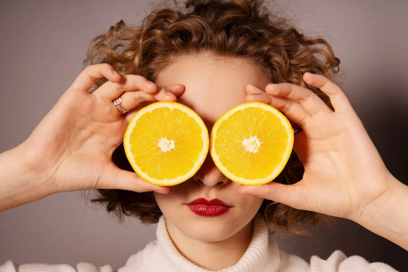 Gros plan sur visage avec fruits jaunes en guise de lunettes, symbole d’une alimentation protectrice pour les yeux.