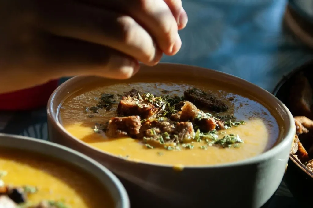 Bol de soupe chaude crémeuse garni de croûtons et herbes, image qui illustre un remède naturel réconfortant pour apaiser une angine.
