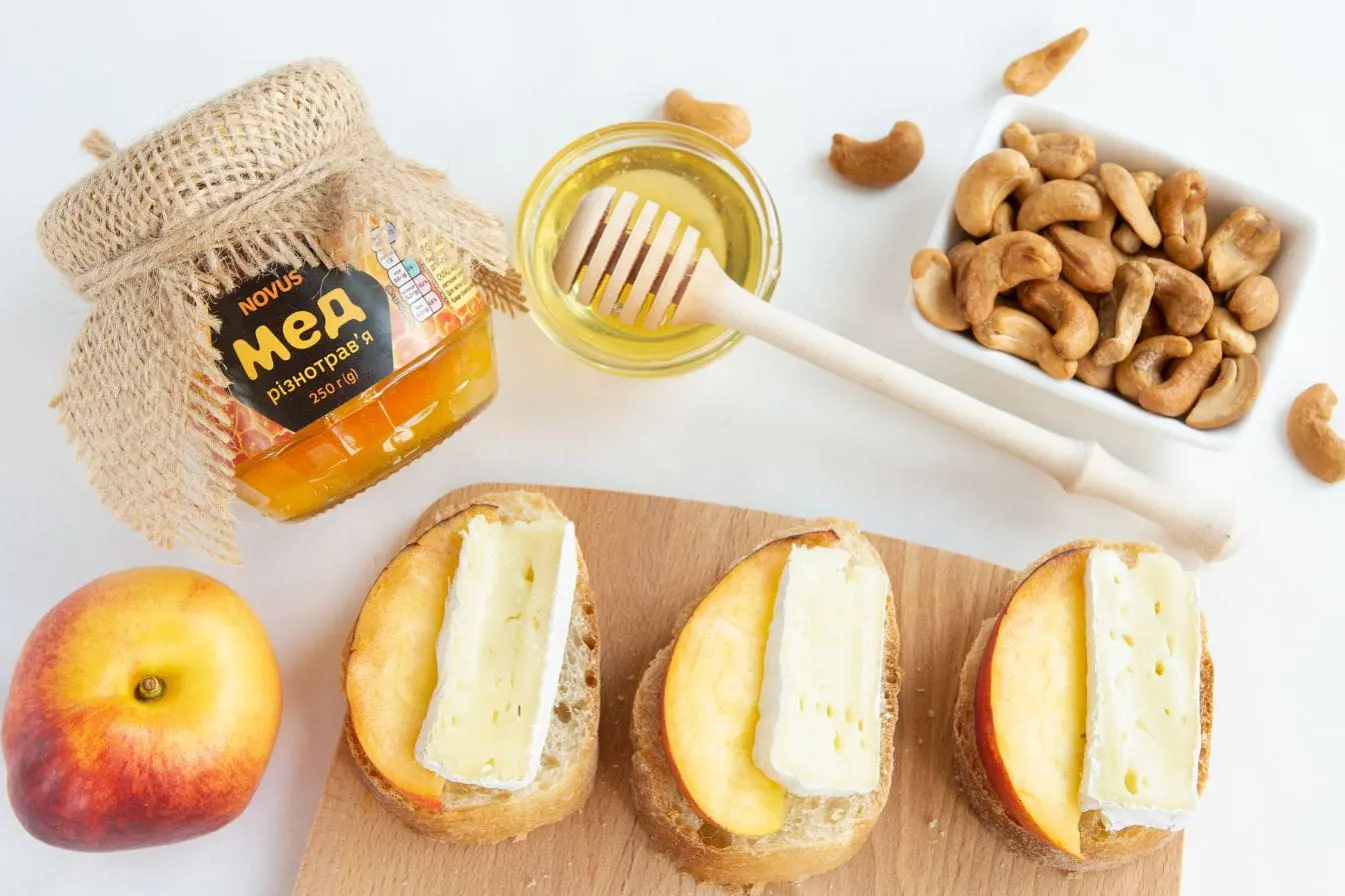 aliments riches en tryptophane Plateau avec miel, noix de cajou et tartines au fromage et nectarine, image qui illustre des aliments riches en tryptophane pour booster le bien-être.