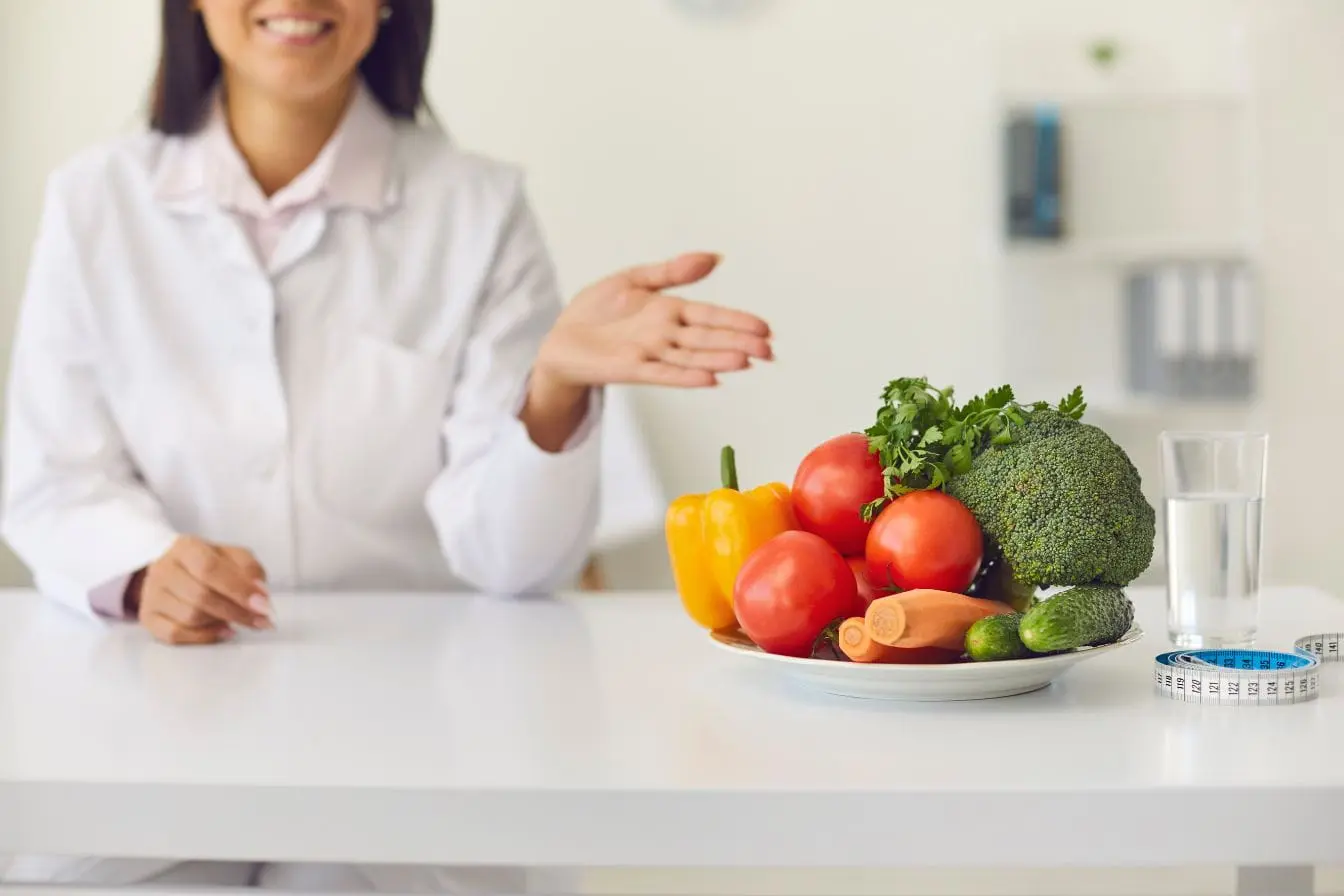 Personne en blouse blanche devant assiette de légumes frais, image qui illustre l’importance d’une alimentation équilibrée pour la santé cardiovasculaire.