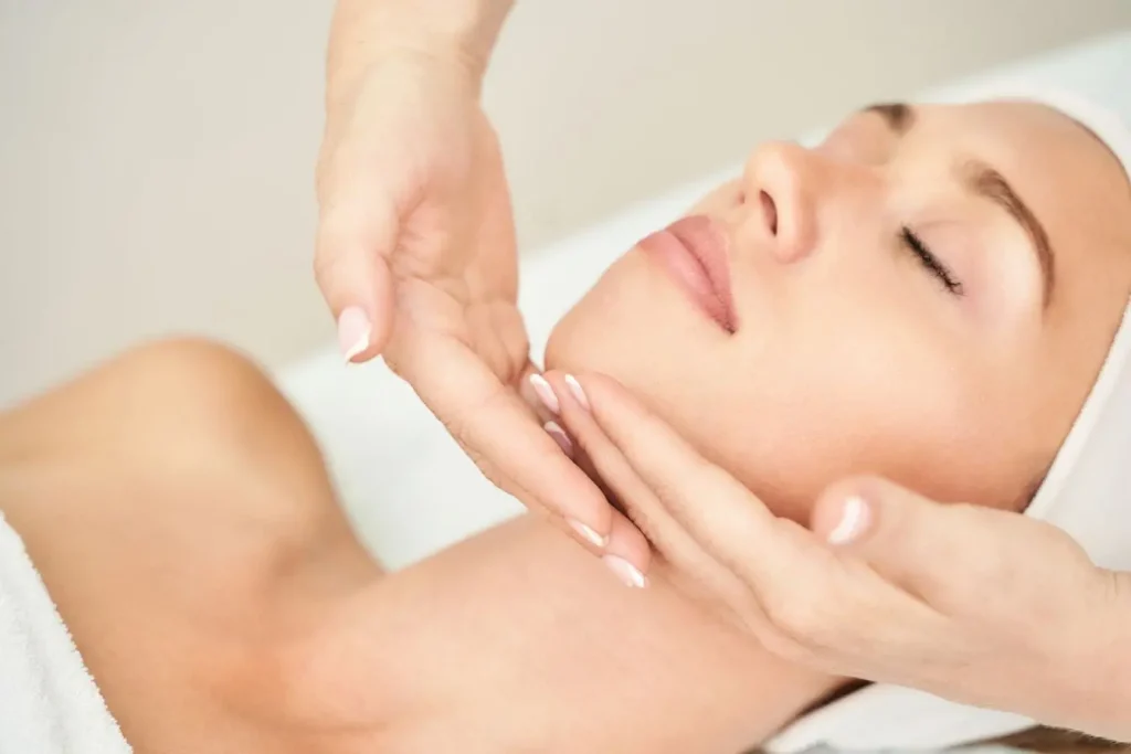 Personne allongée avec bandeau blanc recevant massage du visage, image qui illustre le soulagement recherché face à une névralgie fa