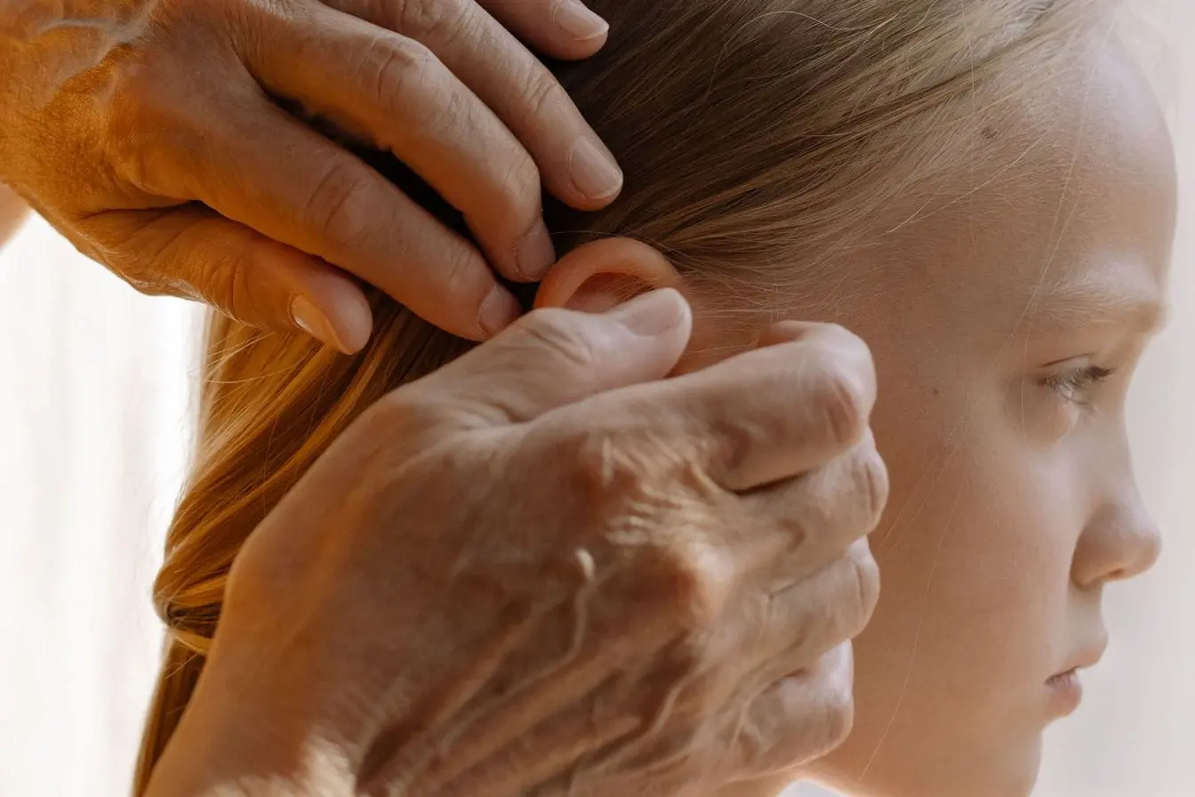 Un praticien effectue un soin doux sur l'oreille d'une personne pour illustrer les bienfaits de la réflexologie auriculaire et de la relaxation profonde