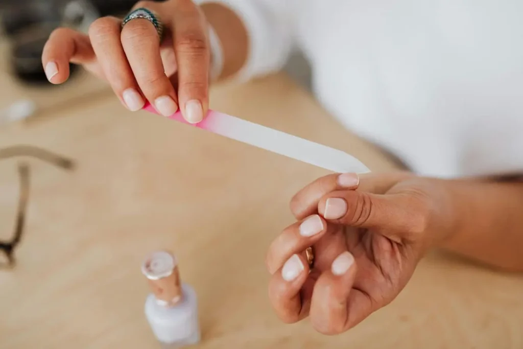 Gros plan sur une lime à ongles en verre utilisée avec soin, image qui illustre le geste délicat pour soigner un ongle incarné.