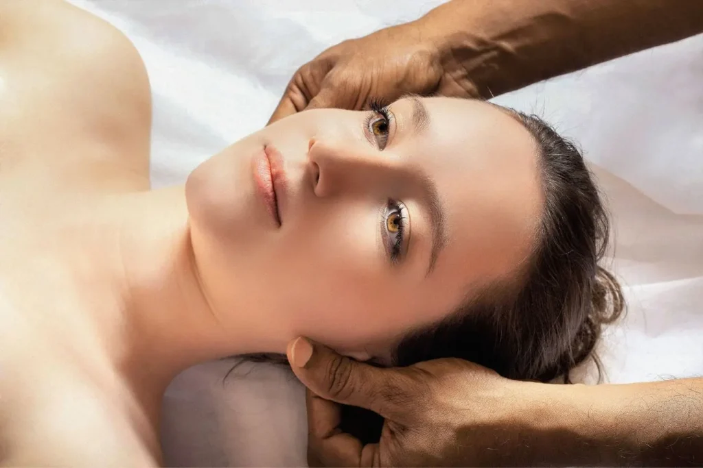 Une femme allongée reçoit un massage des oreilles par un praticien pour illustrer les bienfaits de la réflexologie auriculaire sur la détente et la relaxation