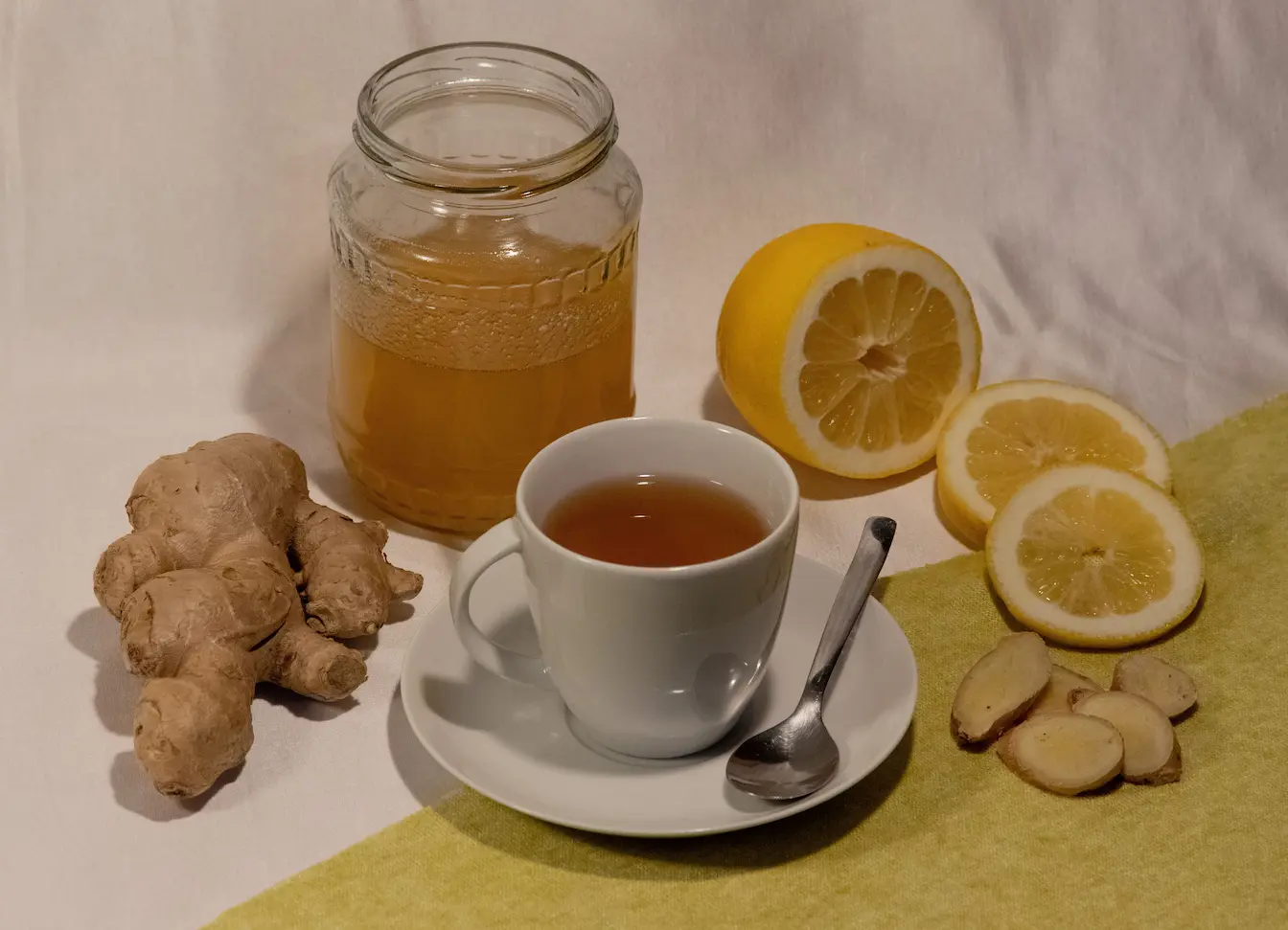 Tasse de thé chaud accompagnée de miel, gingembre et citron, ingrédients naturels utilisés pour soigner un rhume rapidement et efficacement.
