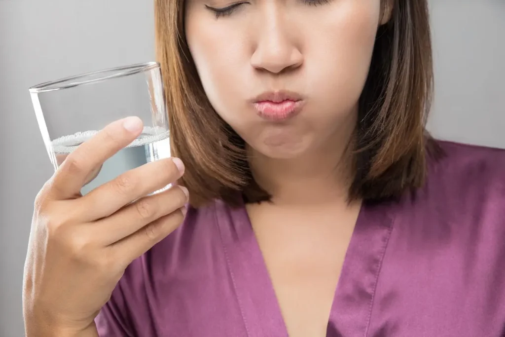 Rinçage buccal avec eau dans bouche et joues gonflées, illustration typique des gestes pour soigner un aphte.