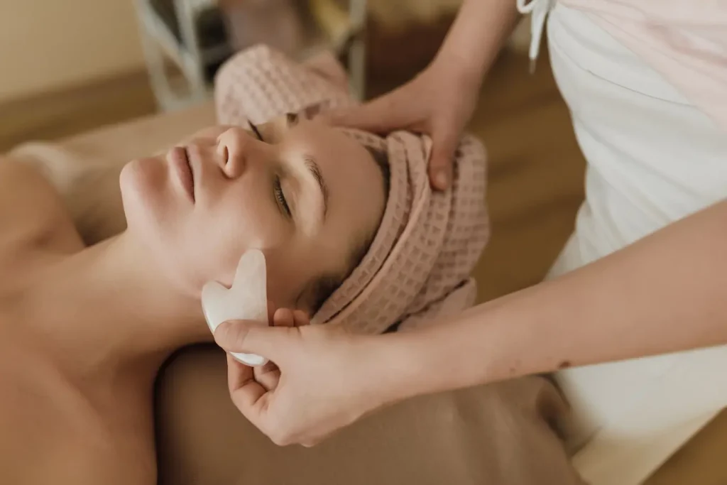 Personne allongée sur lit de spa recevant un massage facial, image qui illustre le stress comme facteur aggravant des cernes creux.