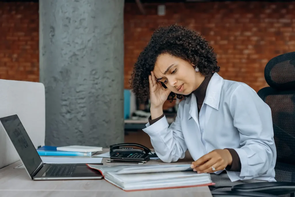Personne en blouse blanche assise à un bureau, image qui illustre le stress comme facteur aggravant des cernes creux.