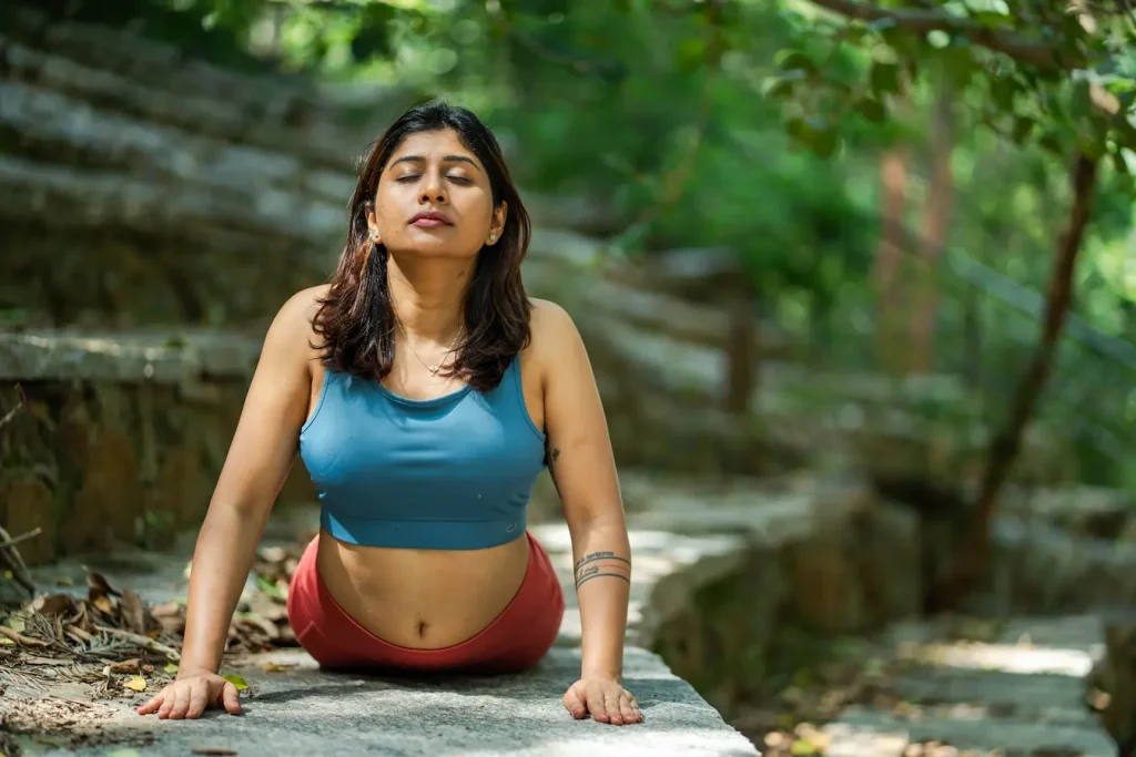 Personne pratiquant le yoga en plein air, image qui illustre une méthode douce pour soulager les acouphènes et apaiser l’esprit.