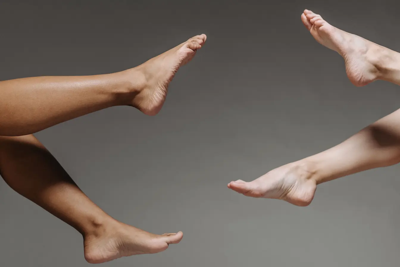 Jambes Deux jambes étendues face à face sur fond gris, symbole des tremblements pouvant révéler un déséquilibre musculaire ou nerveux.