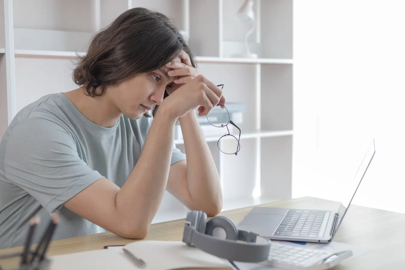 dépression Personne assise à un bureau, main sur le front, symbole de la fatigue mentale et du besoin de soutien.