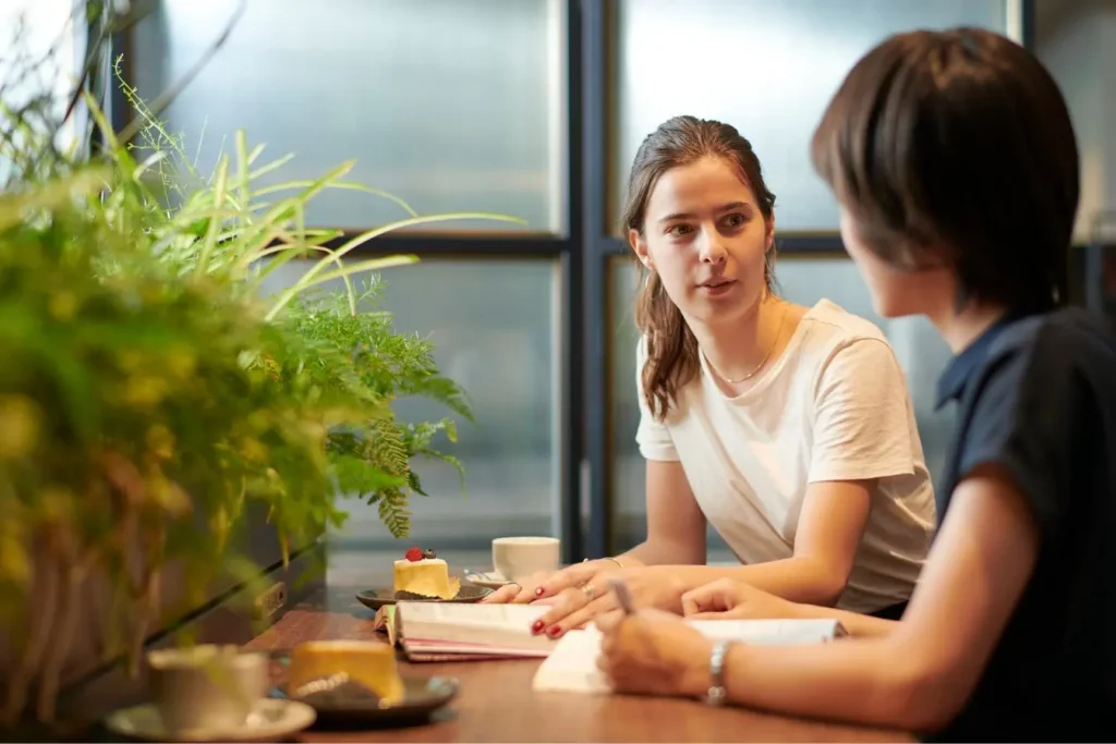 Deux amies discutes calmement dans un café, illustrant l'importance de poser ses limites pour préserver un équilibre relationnel sain.