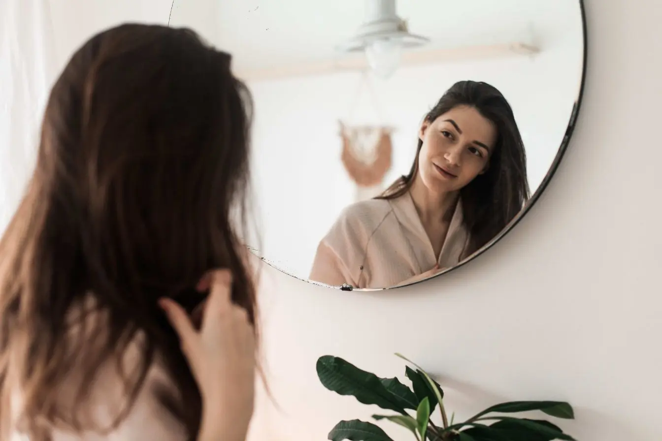 femme souriante Le reflet d'une femme souriante dans un miroir rond qui met en avant la fascination de soi propre au profil narcissique.