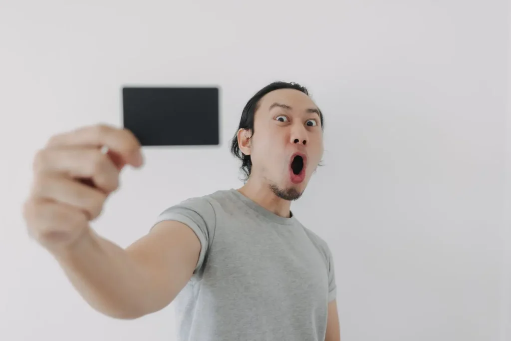 Un homme montre une carte noire avec une expression théâtrale et théâtrale pour attirer l'attention sur lui.