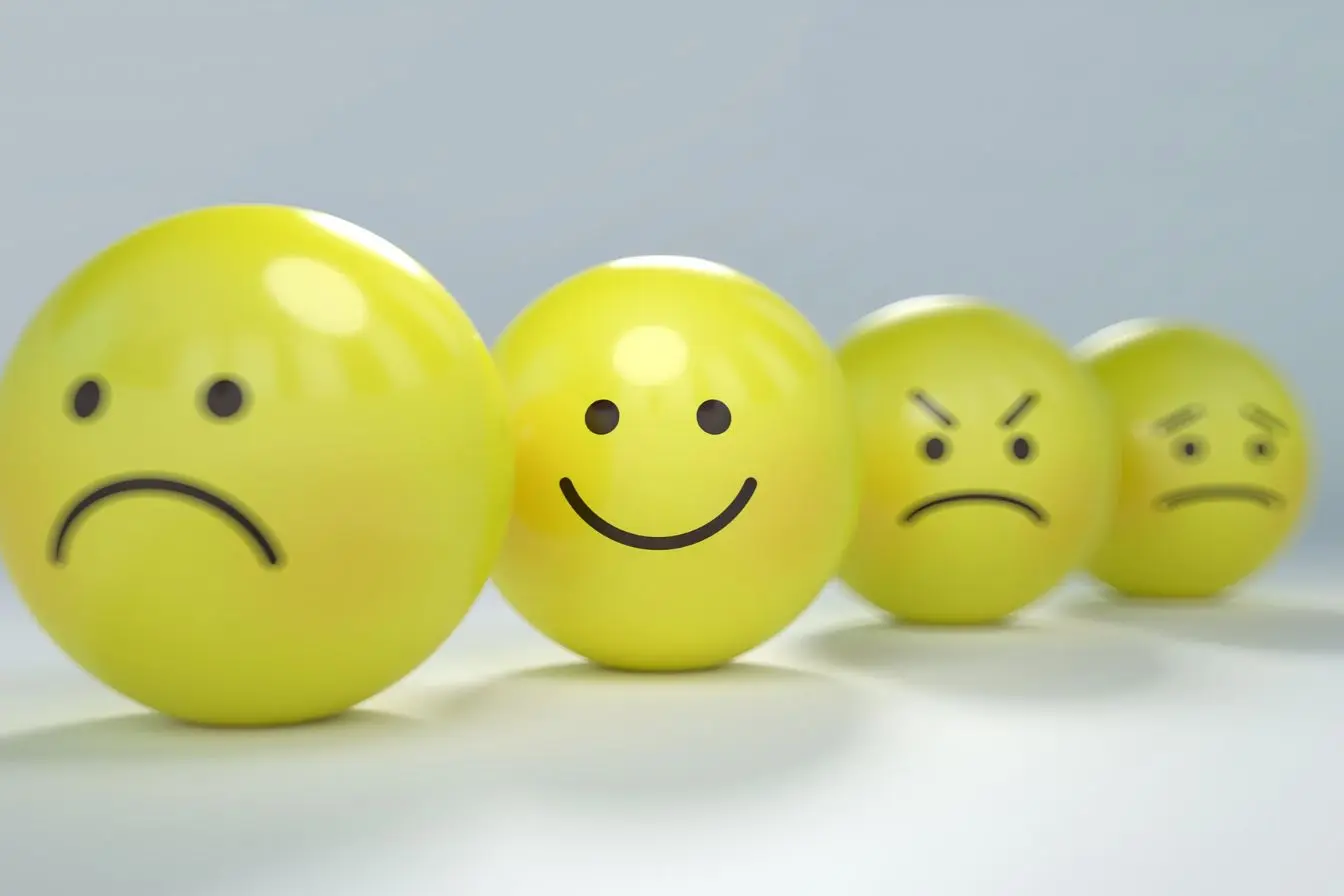 hypersensibilité émotionnelle Des sphères jaunes affichant des expressions contrastées, illustrant le défi de gérer l'hypersensibilité émotionnelle au quotidien.